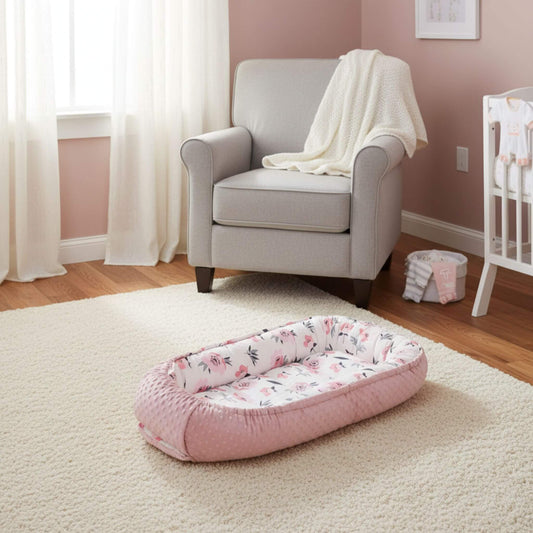 Pink floral baby bassinet in a nursery with a chair and crib.