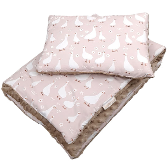 Close-up of nursery bedding set featuring delicate white geese pattern on soft pink cotton background