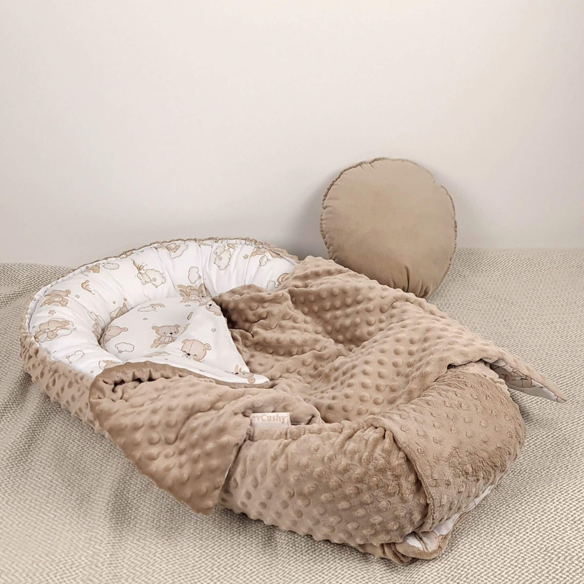 Close-up of the teddy bear cotton print and textured taupe dimple minky fabric on the Evcushy baby nest