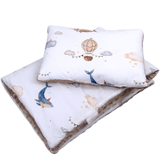 Close-up of cotton fabric baby bedding set featuring whales, clouds and hot air balloons in soft neutral tones