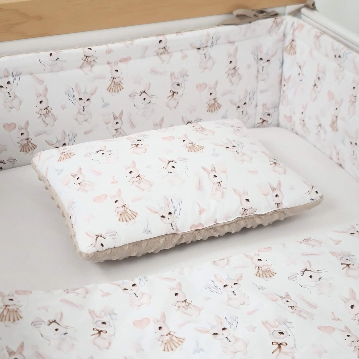 Close-up of retro bunny cotton fabric on cot bed bumper and baby quilt and pillow in a standard crib