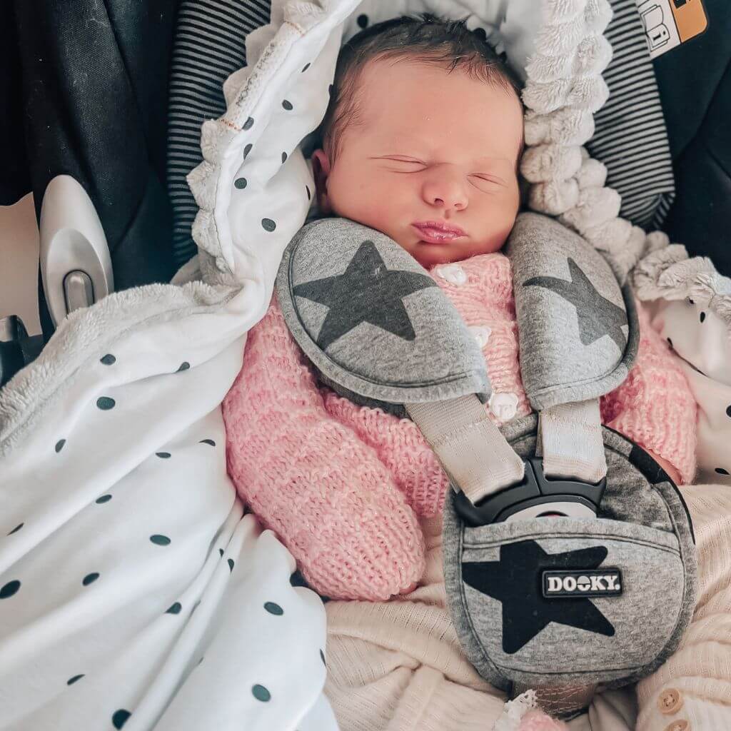 baby in an infant car seat snuggled with blanket with hood in 3 points harness
