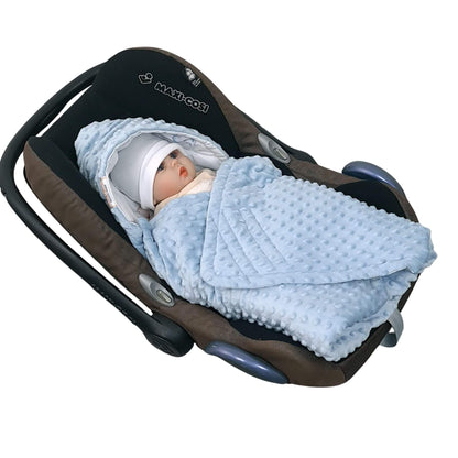 Baby swaddled in a blue blanket in a car seat with Maxi-Cosi branding.