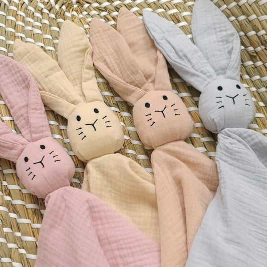 Set of colorful bunny-shaped baby blankets on a woven surface. Evcushy baby comforter – perfect gift for new parents in Ireland