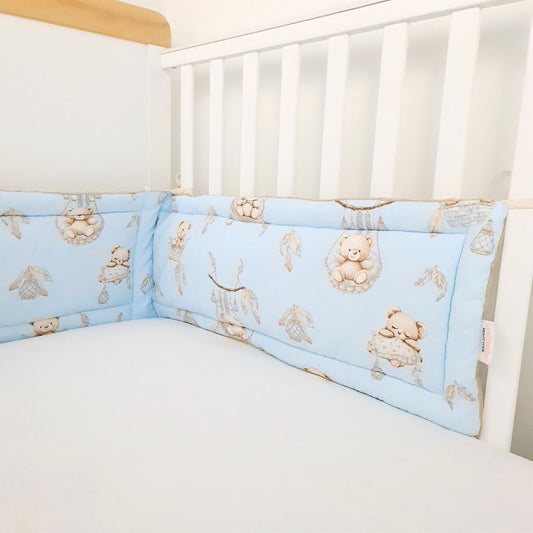 Crib with blue bumper pads featuring teddy bear patterns