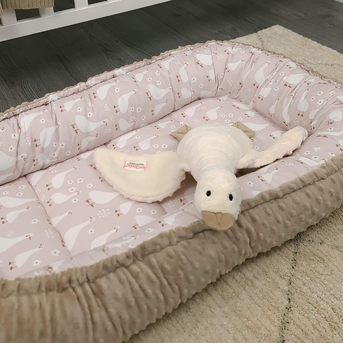 evCushy baby nest sleep pod XXL on the floor carpet portable lounger for baby geese pattern and taupe plush base