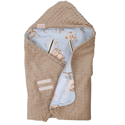 A baby hooded swaddle blanket in beige minky dot fabric, folded to show a light blue inner lining with teddy bear and hot air balloon prints.