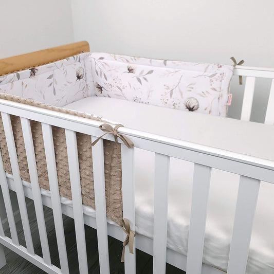 White crib with floral bumper pad  in a neutral room.