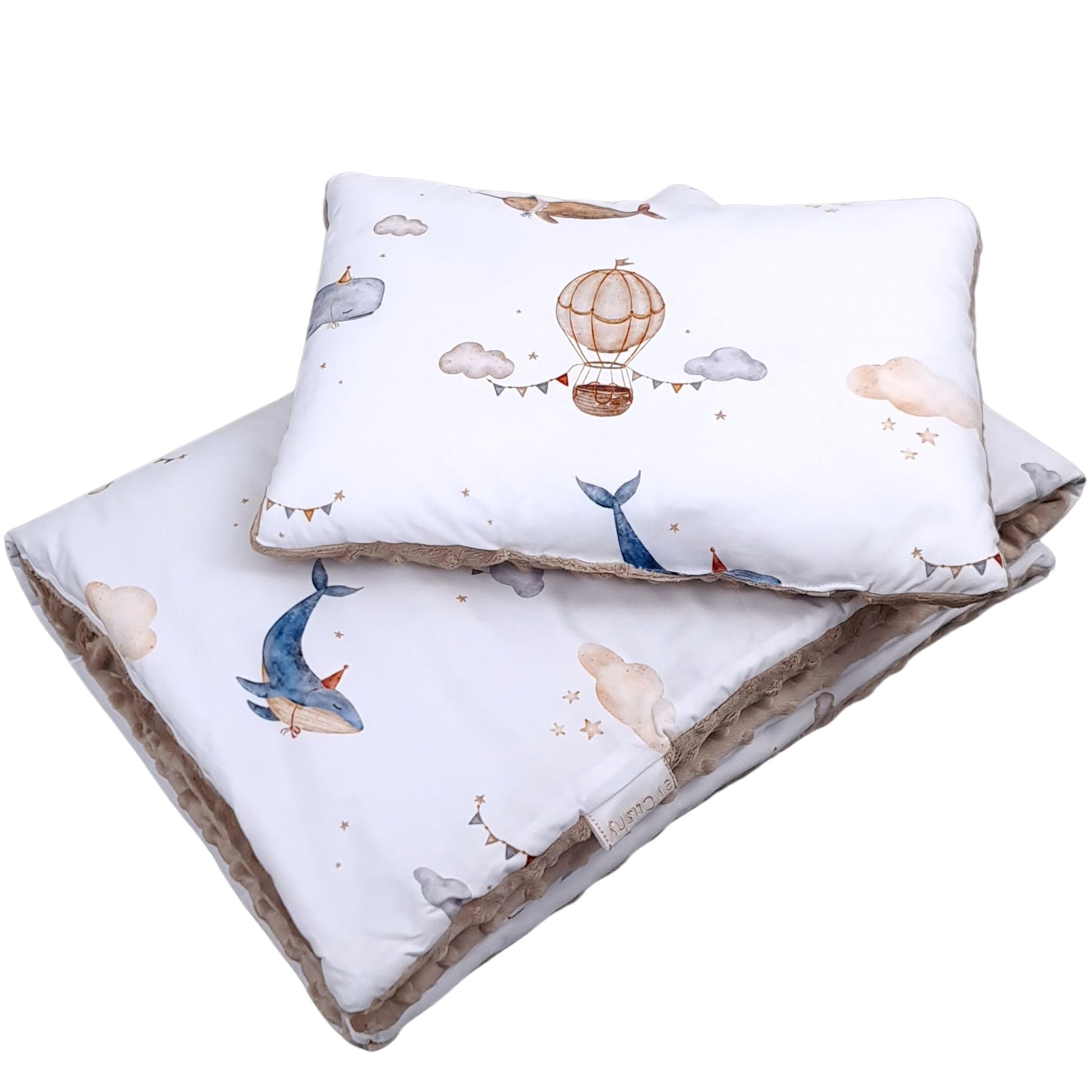 Close-up of cotton fabric baby bedding set featuring whales, clouds and hot air balloons in soft neutral tones