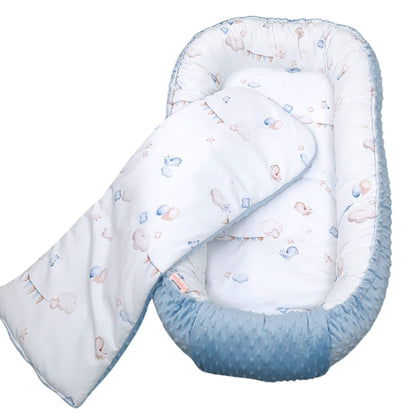 Top view of sky-themed baby nest with clouds, birds and bunting print include also liner all in blue white and beige colours