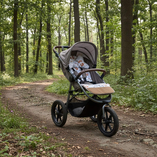 3-wheel stroller with playful forest animals pattern liner on a forest path surrounded by trees and greenery