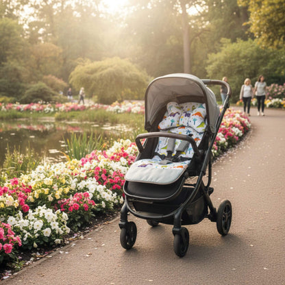 Stroller with small dinosaurs pattern liner on a park alley path beside a calm pond with greenery around