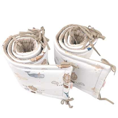 Set of rolled-up cot bed bumpers set liners with straps with balloons and whale pattern
 on a white background