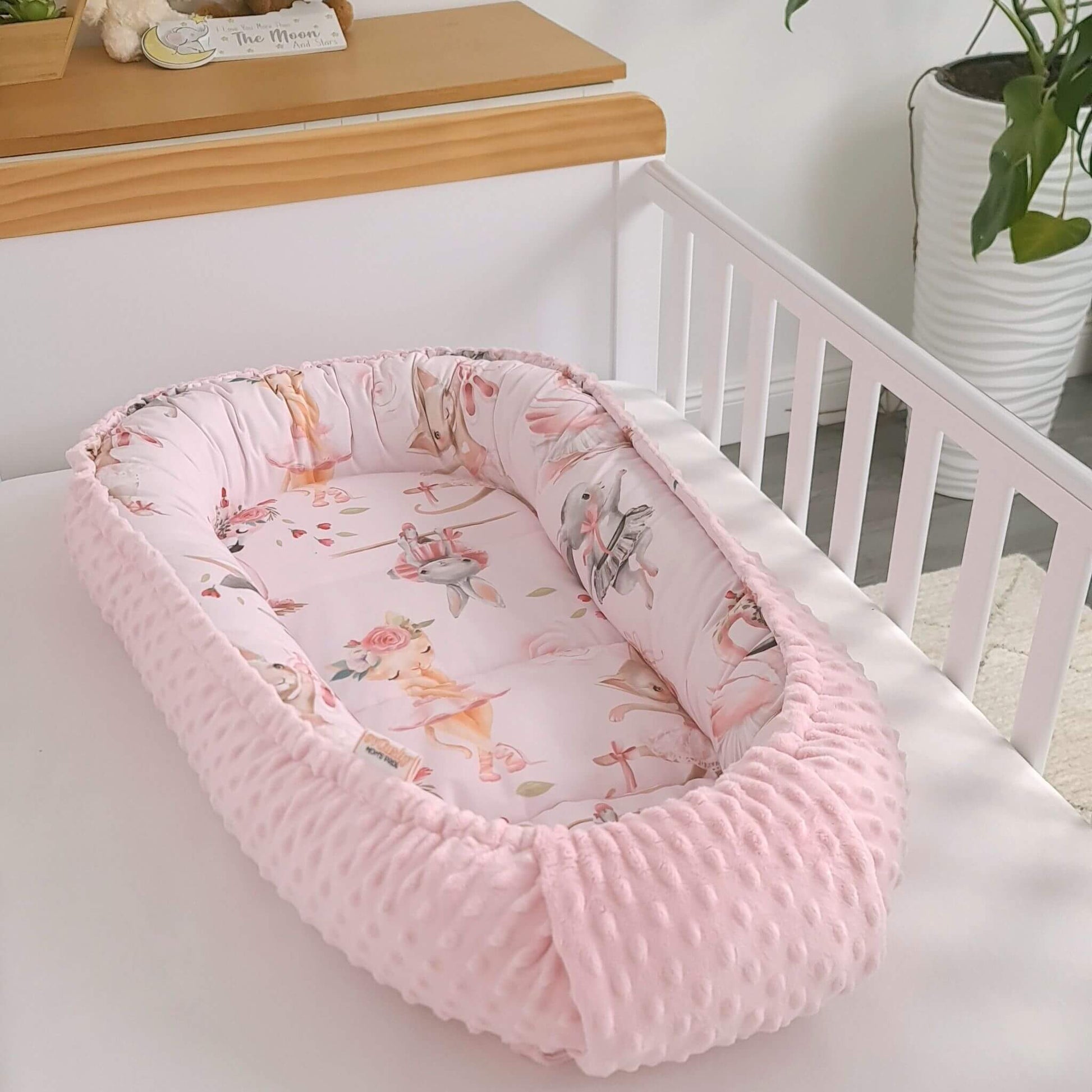 pink baby nest for sleep and lounge with bunnies kittens ballerinas and swans designed in Ireland