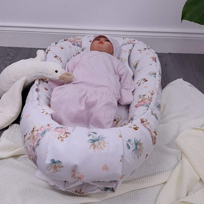 Newborn baby in the nest with matching quilt and pillow featuring lotus flowers and swan pattern, handmade in Europe