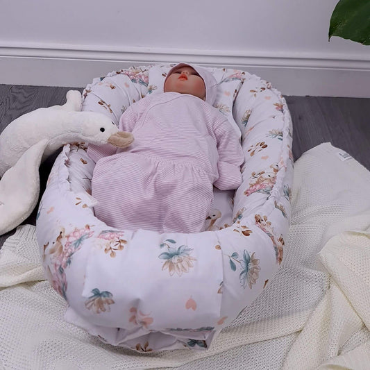 Newborn baby in the nest with matching quilt and pillow featuring lotus flowers and swan pattern, handmade in Europe