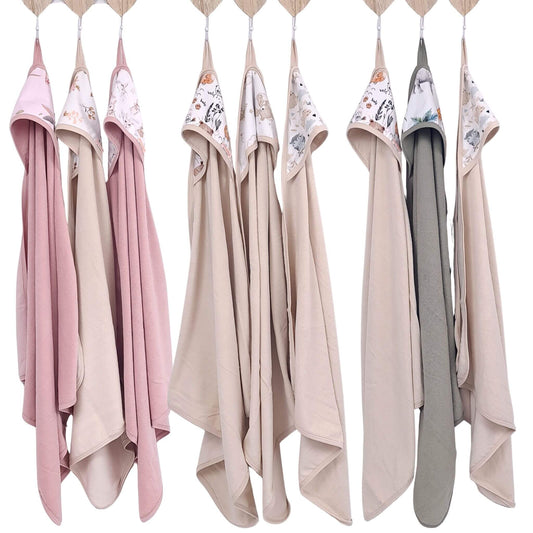 Set of baby bath towels in various colorspink beige sage green hanging on a rack.