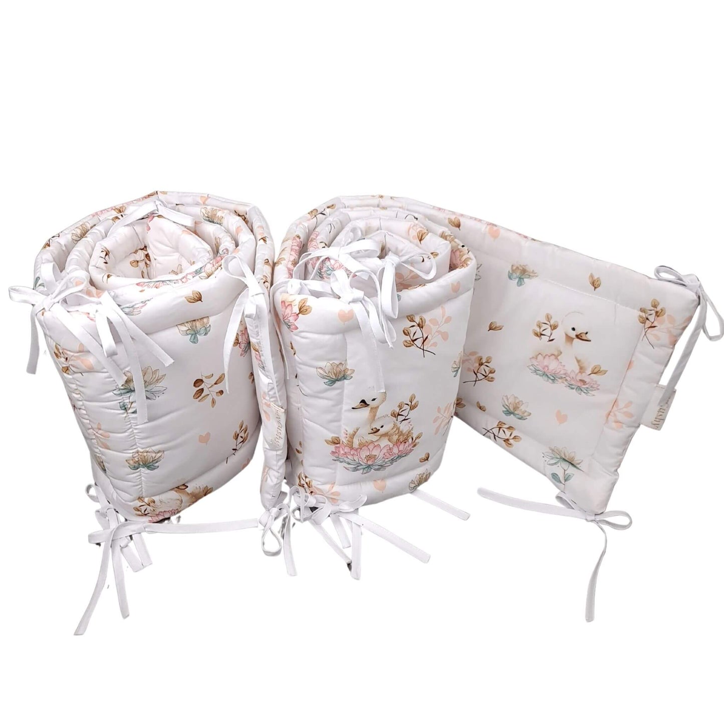 A set of baby crib padded bumpers featuring a delicate pastel floral and duckling pattern on a white background 